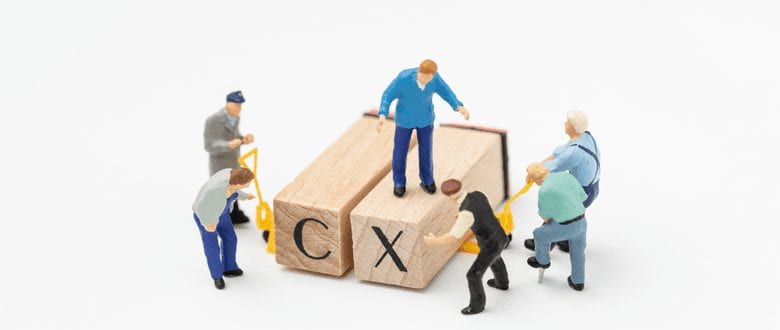 toy figures standing on toy blocks that read C and X against a white background